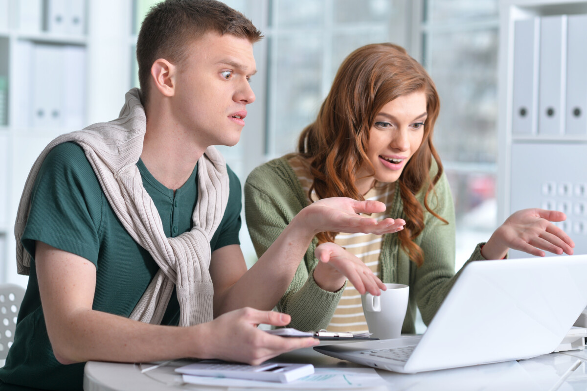 Coworkers looking at computer together with startled expressions.